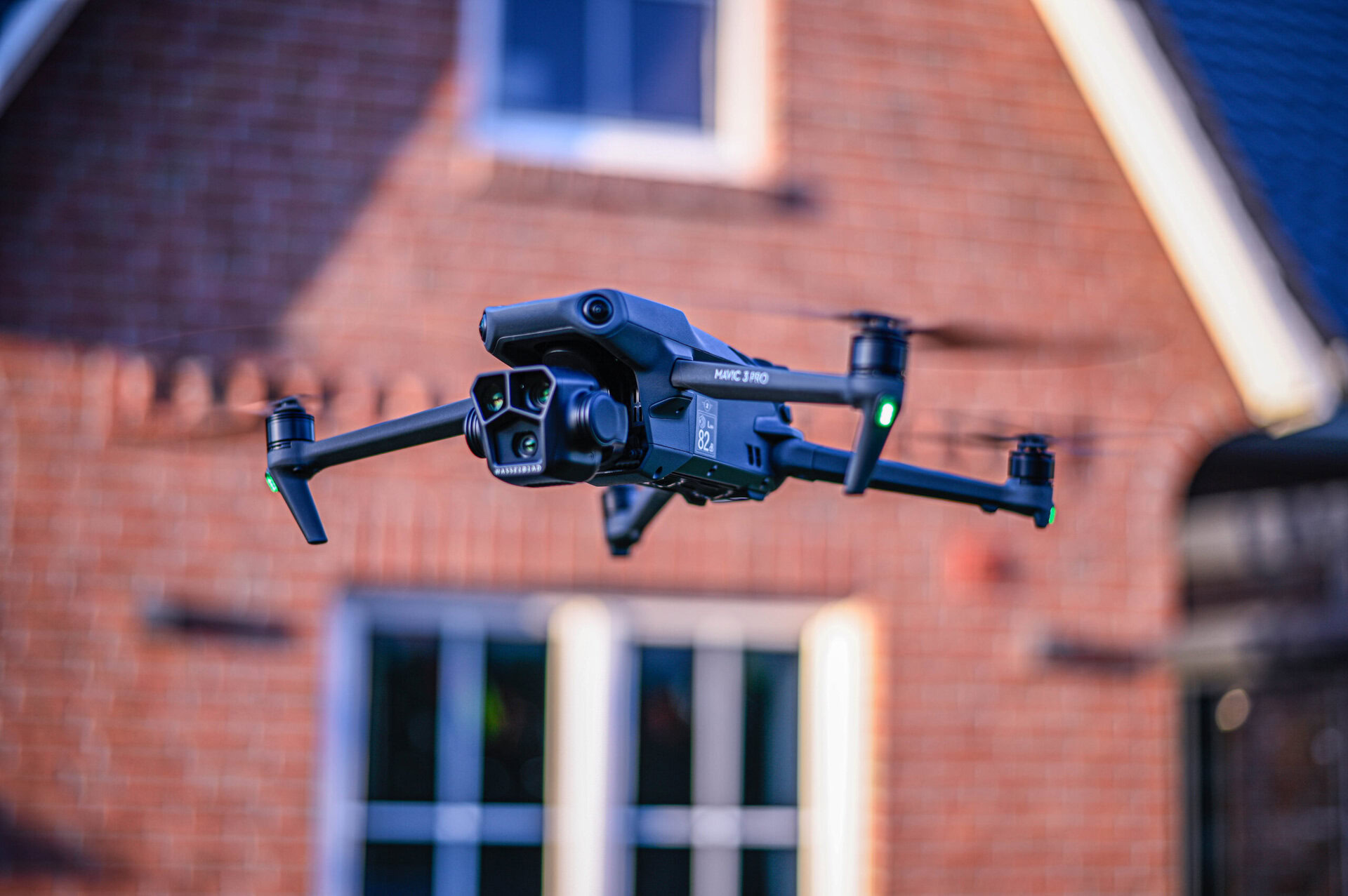 Drohne fliegt vor einem roten Backsteinhaus in der Stadt.